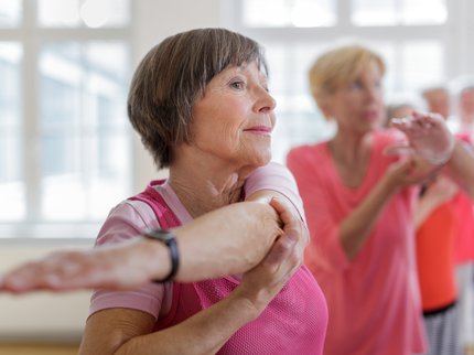 A woman stretching her arms in an excercise class.