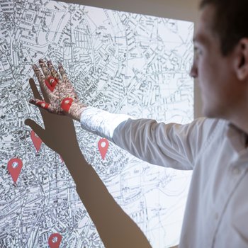 A person touching an interactive historical map on a large screen.