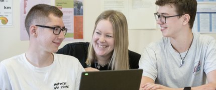 tutor discussing with two college students in front of a laptop