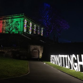 Nottingham castle lit up with a Nottingham light sign in front.