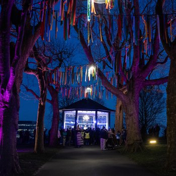 Brightly lit bandstand surrounded by trees and streamers