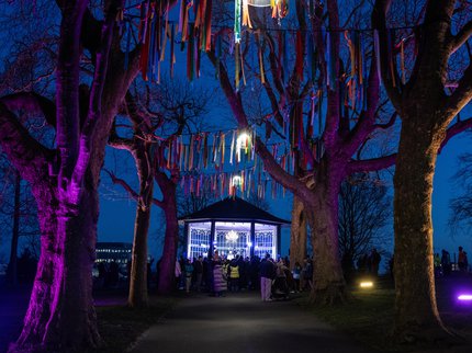 Brightly lit bandstand surrounded by trees and streamers