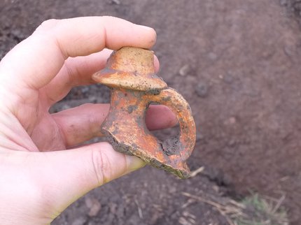 A hand holding the neck of a Roman jug