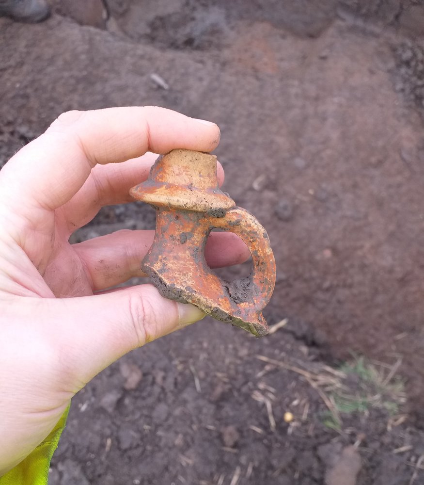 A hand holding the neck of a Roman jug