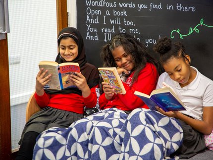 Three girl under  blanket reading