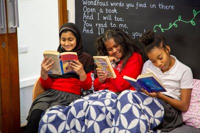 Three girl under  blanket reading