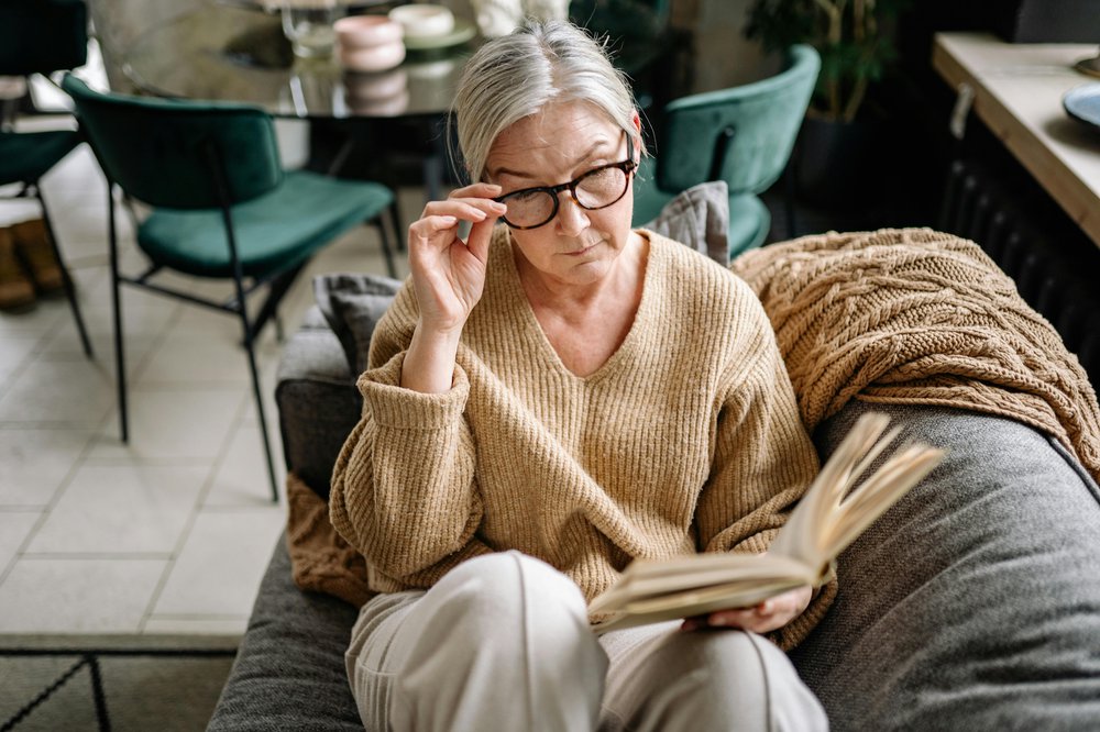 A woman is sat on a sofa reading