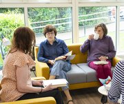 three women sat on a sofa with books in their lap