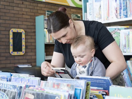 A mother and baby looking at picture books together in a library