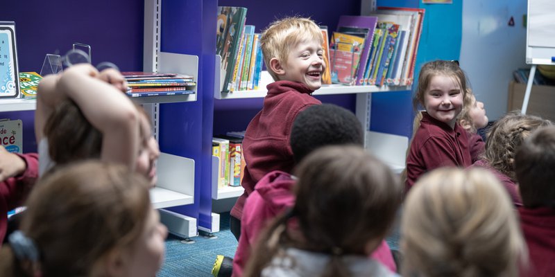 A group of children sat on the floor at Warsop Library, surrounded by book shelves