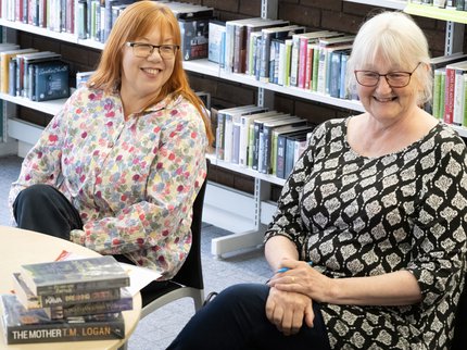 Member of staff holding a stack of books