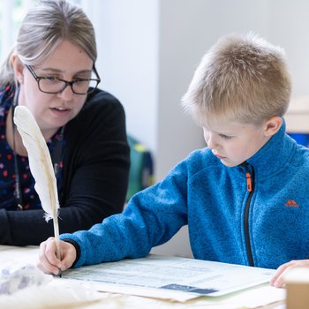 A boy writes with a quill