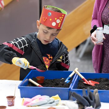 Child planting seeds with help from a stallholder