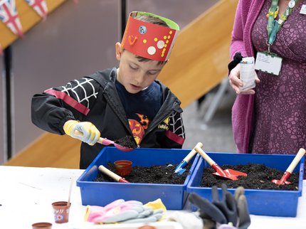 Child planting seeds with help from a stallholder