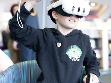 Child wearing a VR headset and holding controllers, with his hands in the air