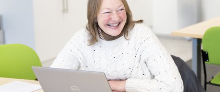 Adult learner smiling sat at a laptop.