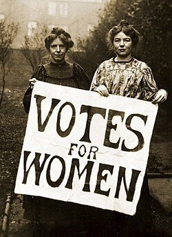 Black and white photo of two women holding a sign reading 'Votes for Women'