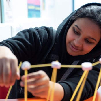 A student building a structure out of dried spaghetti
