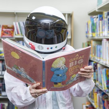 An astronaut reads a book in the Education Library Service