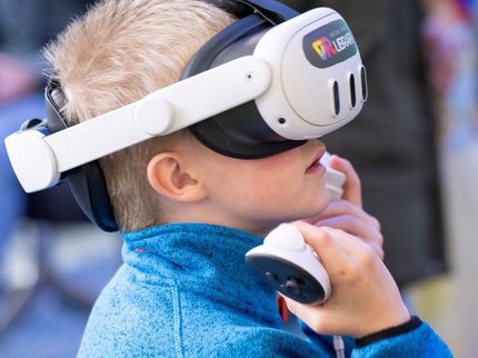 A boy in a blue fleece wears a digital headset