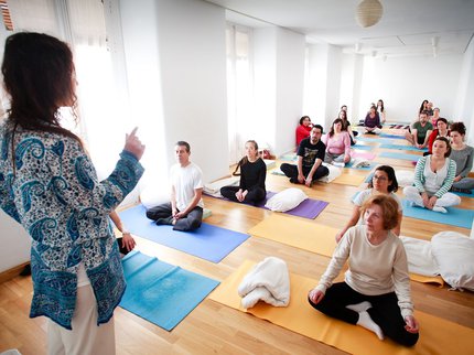 Yoga classroom with people sitting on mats on the floor